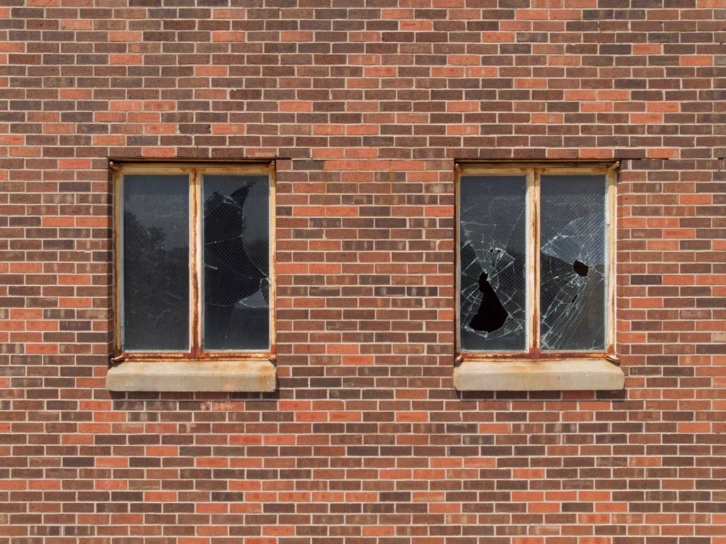 Image of a brick wall with two sets of broken windows