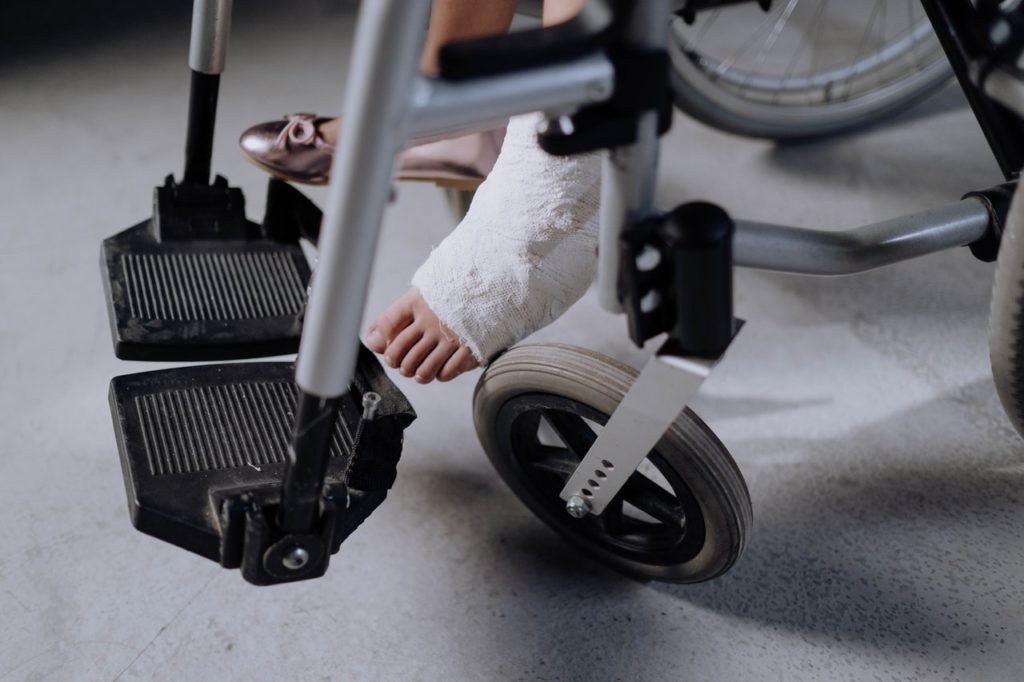 Image of the legs of someone in a wheelchair with a cast on one leg
