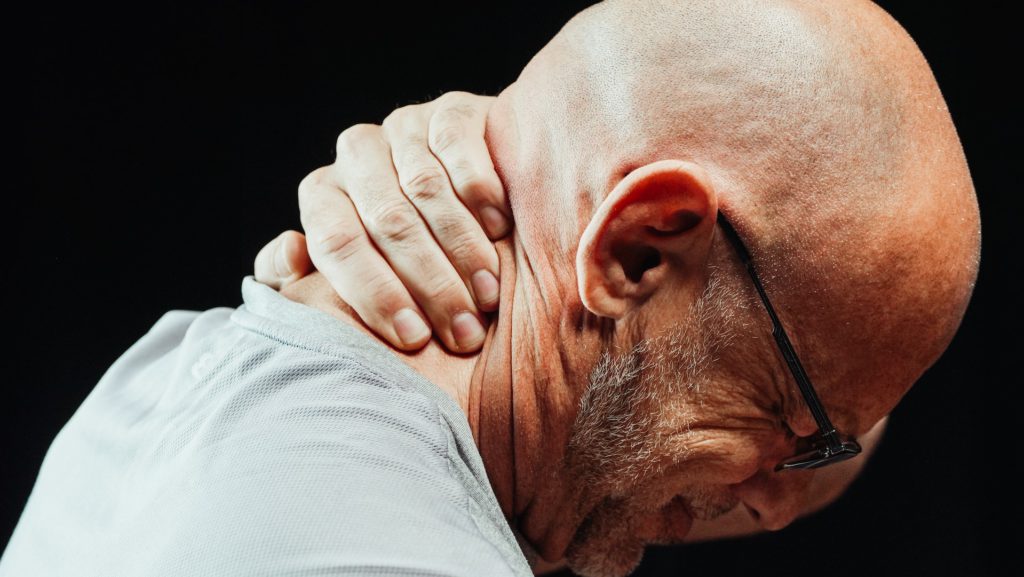 A photo of a man holding his neck in pain