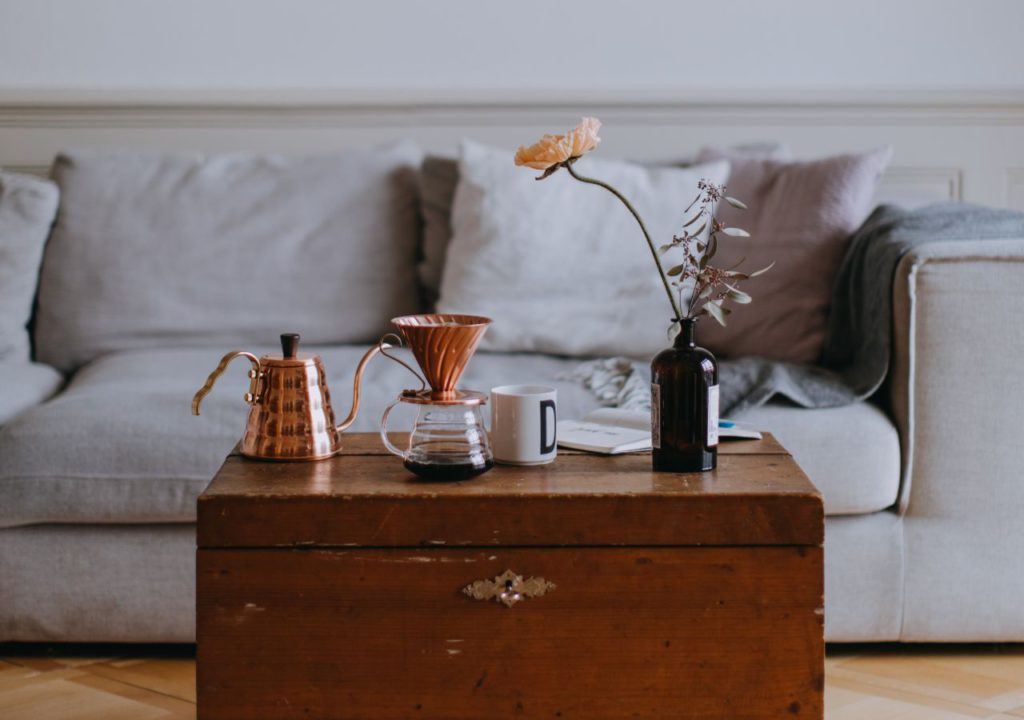 A photo of a short term rental property with a gray sofa and an antique trunk coffee table.